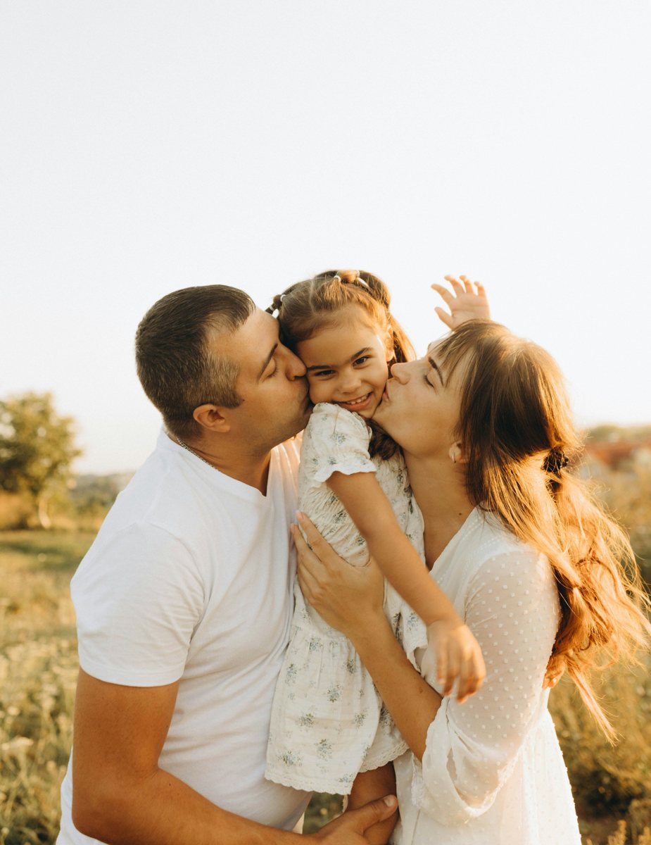 A couple holding their child in warm evening light